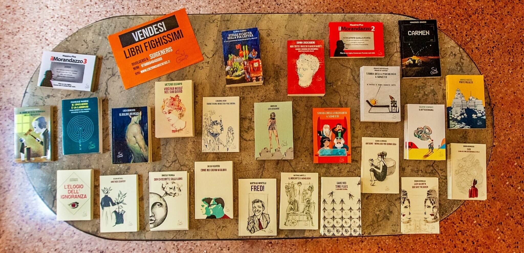 Varietà di libri e copertine pubblicati da SuiGeneris Edizioni, disposti su un tavolo.